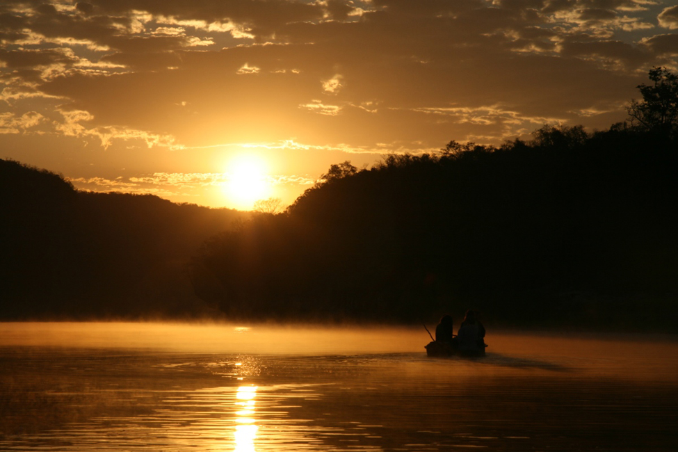 A photo of a boat on a lake at sunset.