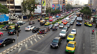 This is a picture of a city street with a traffic signal. The picture has very busy lanes of traffic in both directions.