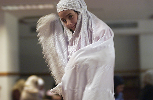 A child in all-white cultural dress is shown.