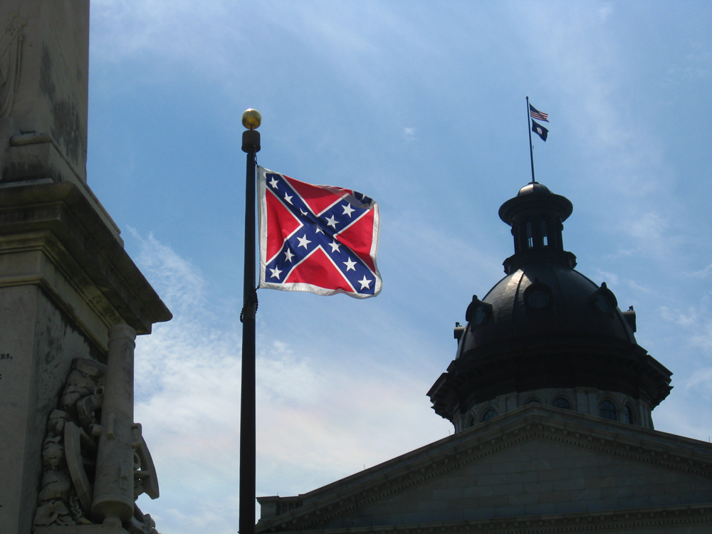 The Confederate flag flying next to the dome of a building.