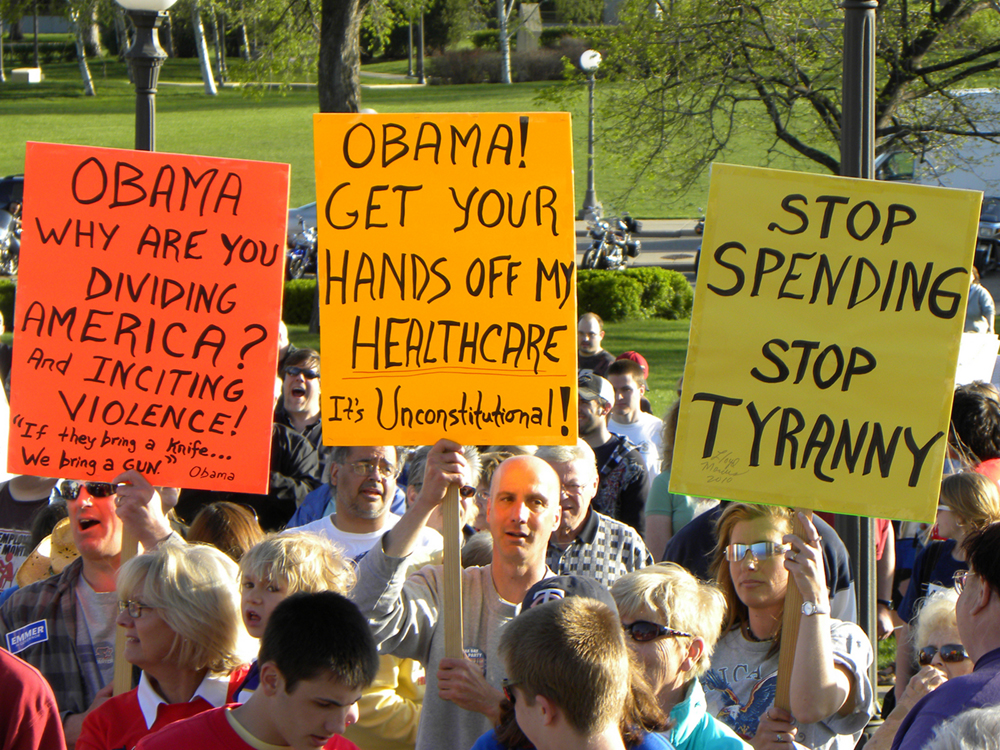 Many people in the United States worry that governmental oversight of healthcare represents a federal overstepping of constitutional guarantees of individual freedom. Others welcome a program that they believe will make healthcare accessible and affordable to everyone. (Photo courtesy of Fibonacci Blue/flickr) A group of protesters holding signs protesting federal health care changes are shown here.